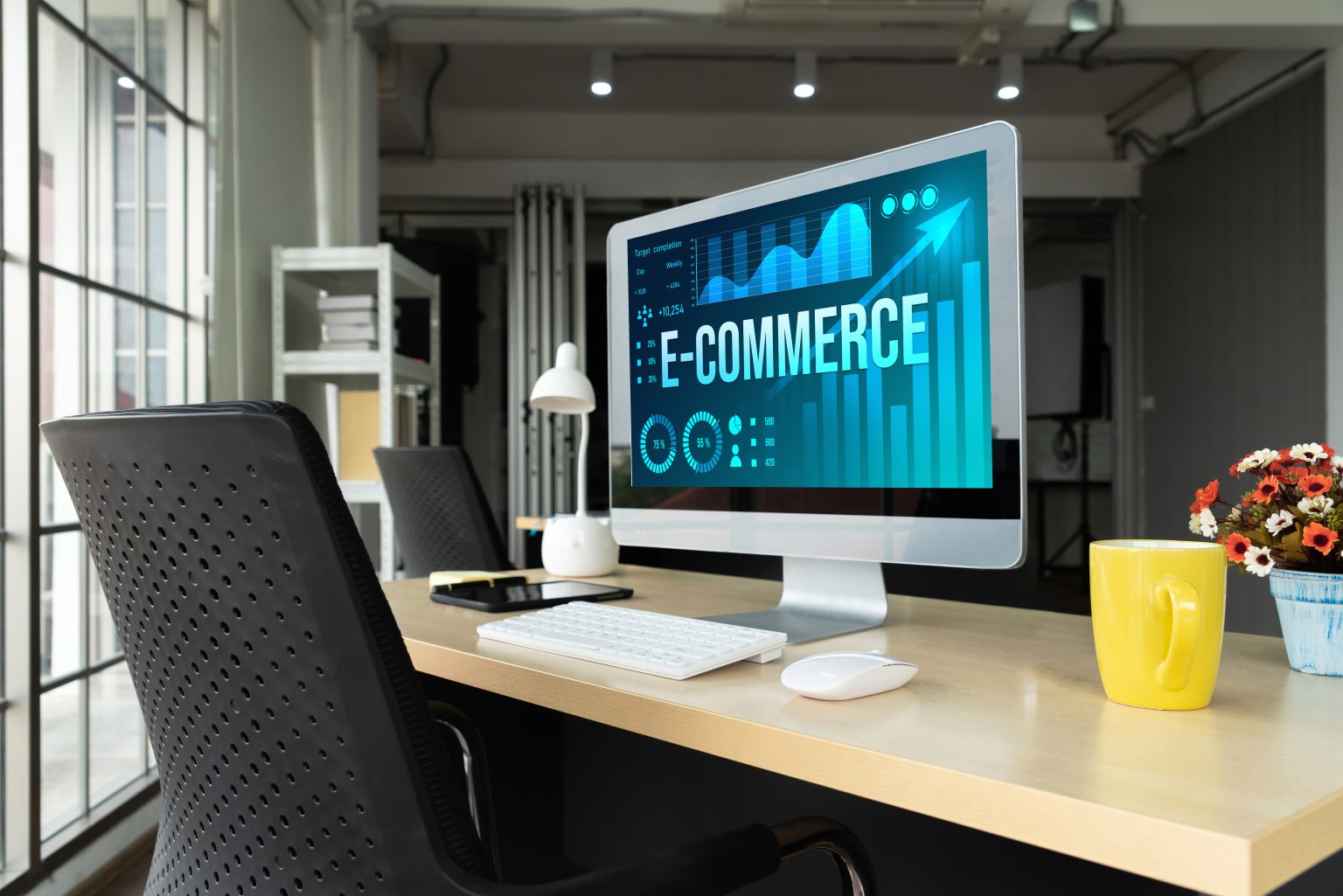 Schreibtisch mit Computerbildschirm, auf dem E-Commerce-Dashboard angezeigt wird, modernes Büro, Sinnbild für die E-Commerce-Lösungen und Marketing-Strategien von komenci.
