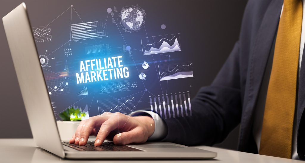 Person in Anzug arbeitet an Laptop mit eingeblendetem Text 'Affiliate Marketing' und digitalen Analysegrafiken, Symbol für erfolgreiche Affiliate-Marketing-Strategien der Agentur komenci.