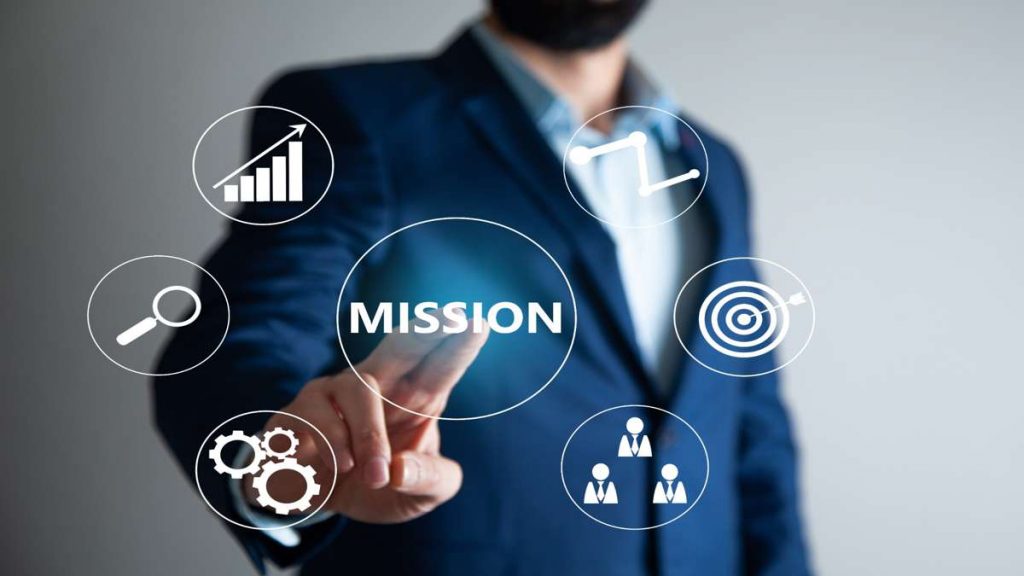 Geschäftsperson tippt auf das Wort Mission mit Symbolen für Wachstum, Strategie und Teamarbeit – Darstellung der Mission der Performance-Marketing-Agentur komenci.
